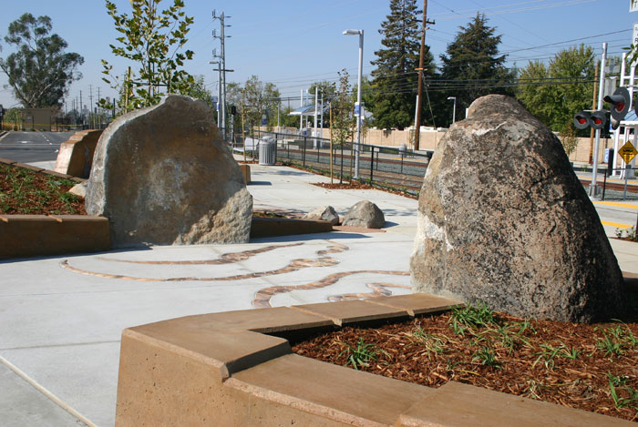 The entryway to the Hazel Light Rail station takes the commuter between a large boulder, split in half. 