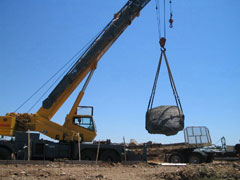 Boulder for entryway to Hazel Light Rail Station being hoisted by a crane onto the site.