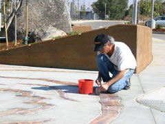 The artist Sam Tubiolo putting finishing touches on inlaid tile at the Hazel Light Rail Station in Sacramento.